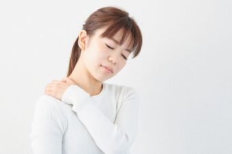 長年の肩こりに悩む女性が肩を押さえている様子
